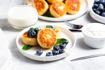 Appetizing cheesecakes with sauce and blueberries on a light background