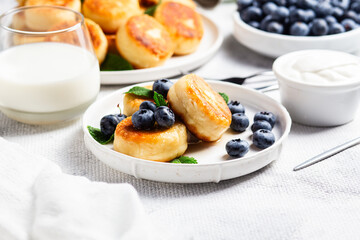 Appetizing cheesecakes with sauce and blueberries on a light background