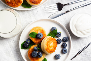 Appetizing cheesecakes with sauce and blueberries on a light background