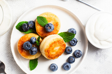 Appetizing cheesecakes with sauce and blueberries on a light background