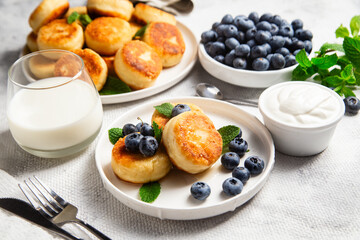 Appetizing cheesecakes with sauce and blueberries on a light background