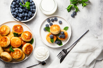 Appetizing cheesecakes with sauce and blueberries on a light background