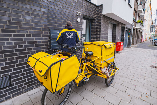 DHL Deutsche Post worker delivering mail with cargo bicycle in front
