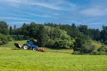 Blue agricultural tractor working in the acre fields to harvest the cereals