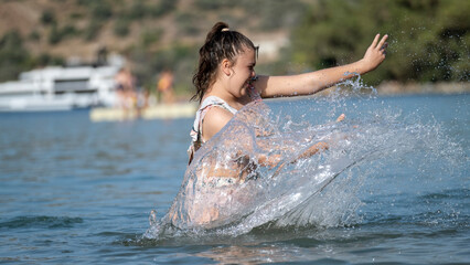 Fototapeta premium A slightly overweight girl happily playing in the sea during vacation
