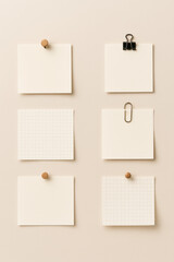 Blank sticky notes attached with binder clips and wooden pins on beige wall