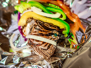 Foil-wrapped lionfish (pterois volitans) with vegetables ready for cooking