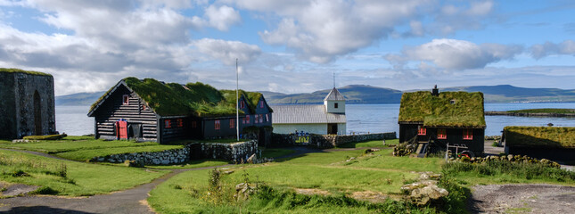 A picturesque village in the Faroe Islands showcases traditional grass-roofed houses along the...
