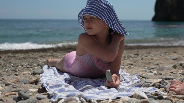 Girl beach summer, child relaxes on pebble seashore, enjoying vacation day