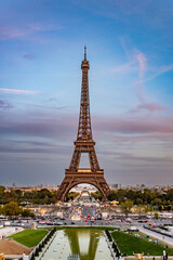 Eiffel Tower at dusk with dramatic sky and city traffic light trails, capturing Paris's vibrant energy.