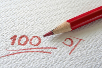 Red pencil marks a perfect score of 100 on a textured white surface