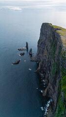 Towering cliffs stand proudly against the tranquil waters of the Faroe Islands, showcasing...