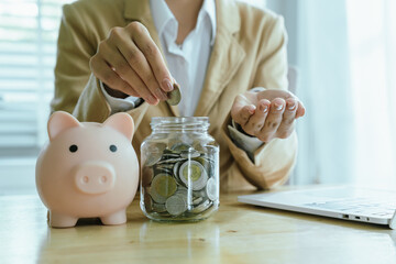 A hand places coins into a growing stack, symbolizing saving, investment, financial planning,...