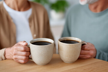 Senior couple holding coffee mugs at home: sharing a moment of relaxation