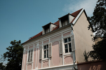 Classic pink building with shutters and dormer windows in Novi Sad, Serbia, against a bright blue sky.