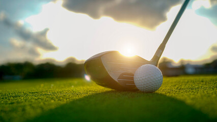 Golf clubs and balls on a green lawn in a beautiful golf course with morning sunshine.