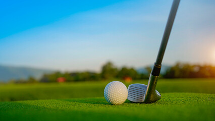 Golf clubs and balls on a green lawn in a beautiful golf course with morning sunshine.