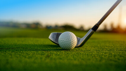 Golf clubs and balls on a green lawn in a beautiful golf course with morning sunshine.