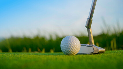 Golf clubs and balls on a green lawn in a beautiful golf course with morning sunshine.