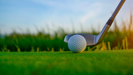 Golf clubs and balls on a green lawn in a beautiful golf course with morning sunshine.