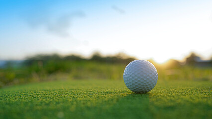 Golf ball on green grass in the evening golf course with sunshine background.