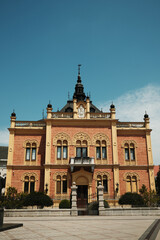 Naklejka premium The Bishops Palace in Novi Sad, Serbia. An ornate building with intricate details and a central tower, photographed on a sunny summer day.