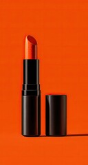 Obraz premium A vibrant orange-red lipstick in a black tube