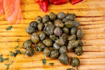 alcaparras encurtidas con pimientos reojos y salmón ahumado en cima de una madera