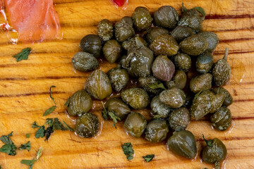 Alcaparras encurtidas encima de una tabla con salmón y perejil