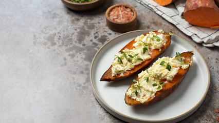 Baked sweet potatoes with creamy cheese topping and fresh herbs. Healthy food. Copy space