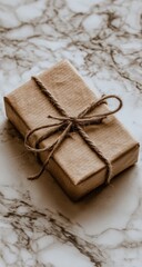 A simple kraft paper gift box tied with twine sits on a marble surface