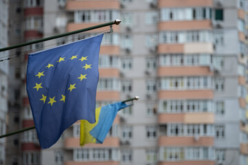 European and Ukrainian flags are prominently displayed in front of residential buildings. The scene captures cultural symbolism and community identity in a vibrant urban setting