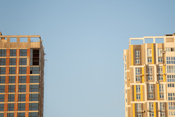 Two contrasting buildings rise majestically, one showcasing completed glass facades while the other...