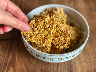 Taking a Piece of Granola from a Bowl on a Wooden Table