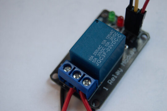 Close up of single channel relay module electronic switch with connected wires on white background for DIY projects and automation.