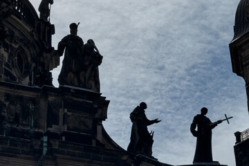 Obraz premium Baroque statues are silhouetted atop medieval building in Dresden