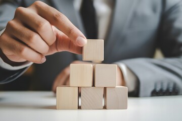 Building a Firm Foundation: A businessperson strategically places wooden blocks, symbolizing the critical construction of a solid groundwork for future expansion and success.