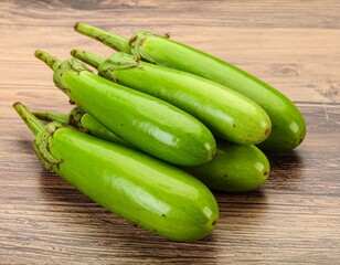 A bundle of green long eggplants stacked diagonally on a wooden surface