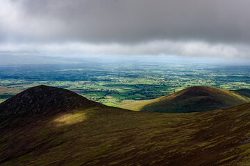 A landscape showcasing rolling hills and verdant valleys in Ireland, viewed from the heights of the...