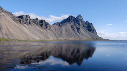 Stunning reflections of Vestrahorn mountain at Stokksnes in Iceland under a clear blue sky
