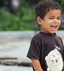 A 20-month-old baby laughing joyfully, with eyes sparkling and mouth wide open, captured in a...