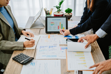 Close up of asian female hands pointing at financial report with graphs and charts on wooden table...