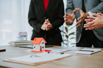 Young couple shaking hands with real estate agent after finalizing their contract, celebrating the exciting purchase of their new home