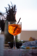 A classic Aperol Spritz cocktail in a glass with a straw sits on inked table