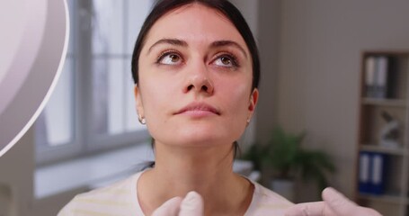 Surgeon touching woman face consulting before rhinoplasty operation. Beautician or cosmetologist examining skin condition to a young girl client. Plastic surgery and beauty concept. 4k video. - Powered by Adobe