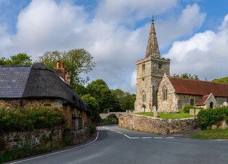 A picturesque village scene in Shorwell on the Isle of Wight, featuring a historic church, charming cottages, and a tranquil road