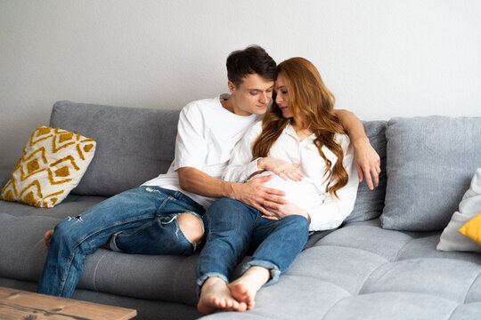 Young couple embracing on a couch expecting a new baby