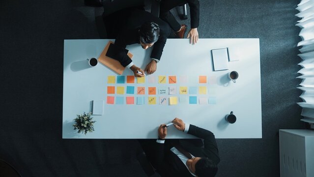 Time lapse of professional business people write and share idea on colorful sticky notes. Top view of smart diverse business man walking and working on sticky papers at meeting table. Directorate.