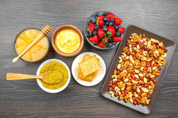 Healthy snack platter featuring assorted nuts, honey, and fresh berries on wooden background