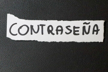 A close-up view of a torn piece of paper with the word CONTRASEÑA written in bold letters. The...
